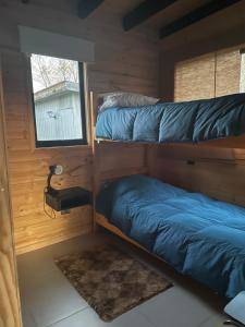 two bunk beds in a room with a window at Cabaña Negra in Riñinahue