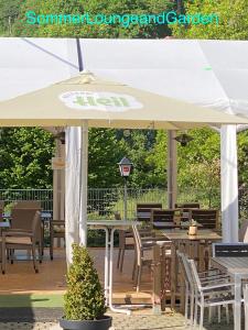 an umbrella on a deck with tables and chairs at Gasthaus "Zur frischen Quelle" in Laubach
