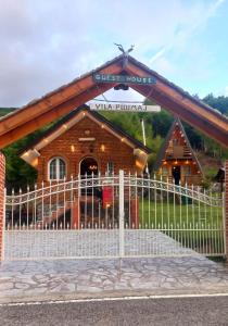 uma casa de hóspedes de madeira com uma cerca em frente em Vilat Pllumaj em Gropat e Selcës