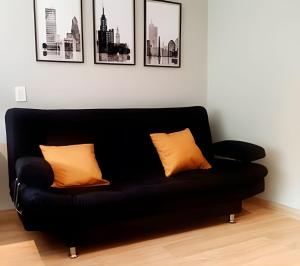 a black couch with two orange pillows in a room at Loft Ejecutivo, vista panorámica, Usaquén Bogotá in Bogotá