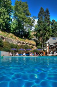 uma piscina com cadeiras e guarda-sóis num resort em Hotel Les Chalets em Brides-les-Bains