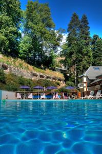 a swimming pool with chairs and umbrellas on a resort at Hotel Les Chalets in Brides-les-Bains