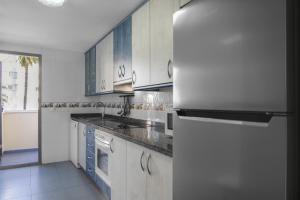 a kitchen with white cabinets and a refrigerator at Apartamentos Hipocampos Calpe Rent Apart in Calpe