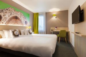 ein Hotelzimmer mit einem großen Bett und einem TV in der Unterkunft The Originals City, Tabl'Hôtel, Amiens in Longueau
