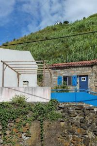 a house on top of a hill with a blue door at Casa da Avó Madalena in Fayal da Terra