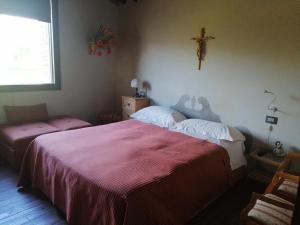 - une chambre avec 2 lits et une croix sur le mur dans l'établissement Casetta dell`Uliveto, à Macchiascandona