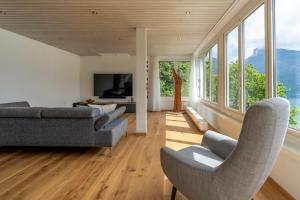 een woonkamer met een bank, stoelen en ramen bij Best of Lake Site in Spiez