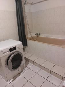 een badkamer met een wasmachine en een bad bij Dominique et Françoise in Fourques-sur-Garonne