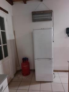 een witte koelkast in een keuken met een rode blusser bij Dominique et Françoise in Fourques-sur-Garonne