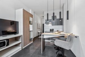 a kitchen with a dining table and a tv at Erba Retreat! Barrierefreies, modernes 1-Zimmer-Appartement in optimaler Lage! in Bamberg +2 photos