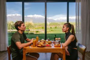 Um homem e uma mulher sentados à mesa com comida. em La Morada Lodge em Vista Flores