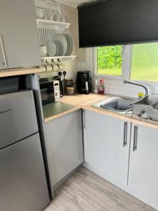 a kitchen with white cabinets and a sink and a window at Woodlands Pheasant Chalet, Bideford Bay in Bideford