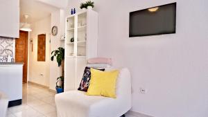 a living room with a white chair with a yellow pillow at White studio in Torrevieja