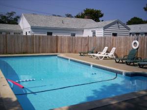 a swimming pool with two chairs and a fence at 194 Captain Chase Road Dennis Port Cape Cod - - Beach Retreat I in Dennis Port