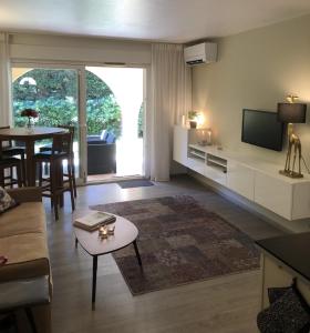 sala de estar con sofá, TV y mesa en Les Jardines d`Artemis (27) en Saint-Tropez