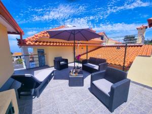 un patio avec des chaises et un parasol sur le toit dans l'établissement Casa en centro de Santana con vista al mar y la montaña, à Santana