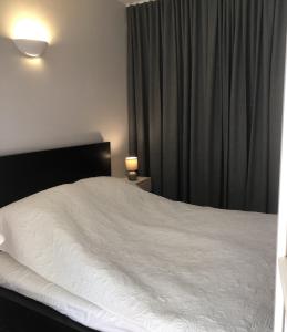 1 dormitorio con cama blanca y cortinas negras en Les Jardines d`Artemis (27) en Saint-Tropez