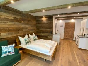 a bedroom with a wooden wall with a bed and a couch at Stylisches Chalet im Schlosspark Grubhof mit Innenpool und Balkon in Sankt Martin bei Lofer