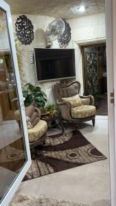 a living room with two chairs and a flat screen tv at شقه مفروشه مع حديقه اربد بجانب فندق فلامنجو ومدارس دار العلوم in Irbid