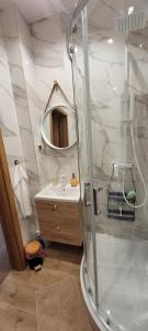 ein Badezimmer mit Dusche, Waschbecken und Spiegel in der Unterkunft Gold Apartament in Olsztyn