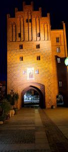ein großes Backsteingebäude mit einem Torbogen bei Nacht in der Unterkunft Gold Apartament in Olsztyn