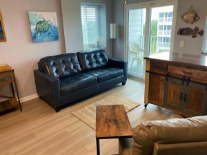 a living room with a black leather couch and a table at Gulf Shores Plantation Condos in Gulf Shores