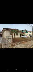 einen Zaun vor einem Gebäude mit geparkten Autos in der Unterkunft Alojamentos in Telêmaco Borba