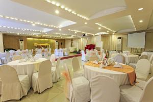 un salón de banquetes con mesas y sillas blancas y una pantalla en The Orchard Cebu Hotel & Suites en Cebu City