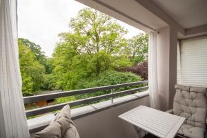 a balcony with a table and a view of trees at Park Szczytnicki 2-Bedroom Apartment in Wrocław
