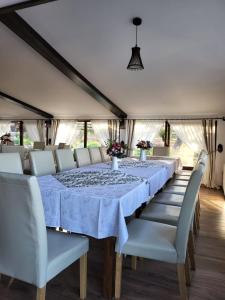 a long dining room with a long table and white chairs at Pensiunea La Voicut in Sohodol