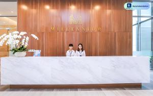 two people standing behind a counter in a lobby at Blissful Apartment - Masteri Millennium - FREE Infinity Pool in Ho Chi Minh City