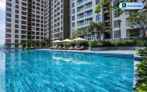 a large swimming pool with chairs and umbrellas in front of buildings at Blissful Apartment - Masteri Millennium - FREE Infinity Pool in Ho Chi Minh City
