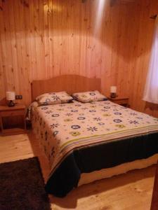 Schlafzimmer mit einem großen Bett und Holzwänden in der Unterkunft Cabaña en Dalcahue in Dalcahue