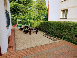 Un patio con bancos y mesas y un seto. en Villa Alex, en Władysławowo