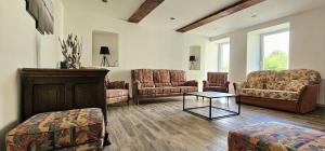 a living room with couches and a table at Maison Saint Côme du Mont in Saint-Côme-du-Mont