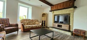 a living room with a fireplace and a tv at Maison Saint Côme du Mont in Saint-Côme-du-Mont +2 photos