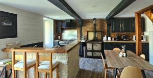 a kitchen with a counter and a table with chairs at Maison Saint Côme du Mont in Saint-Côme-du-Mont