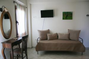 a bedroom with a couch and a desk and a mirror at Studios Liotrivi Ouranoupolis in Ouranoupoli