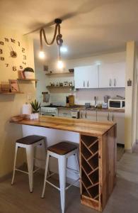 a kitchen with a wooden counter and two stools at Ritasol Palace apartamento de relax frente al mar in Caraballeda
