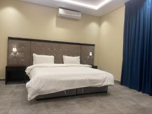 een slaapkamer met een groot bed en een blauw gordijn bij شقق درر رامه للشقق المخدومة 11 in Riyad