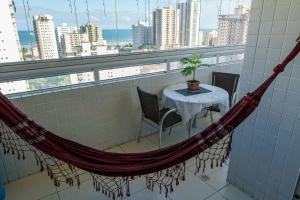 uma rede num quarto com mesa e cadeiras em VISTA PRAIA MAR - AVIAÇÃO - 300 metros da praia - WI FI - VARANDA GOURMET com CHURRASQUEIRA - ESTACIONAMENTO gratuito na Praia Grande