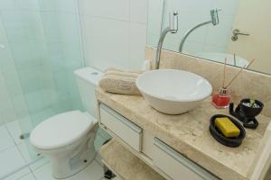 ein Badezimmer mit einem Waschbecken, einem WC und einem Spiegel in der Unterkunft VISTA PRAIA MAR - AVIAÇÃO - 300 metros da praia - WI FI - VARANDA GOURMET com CHURRASQUEIRA - ESTACIONAMENTO gratuito in Praia Grande