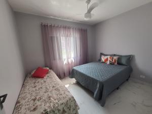 um quarto com 2 camas e uma janela em BEIRA MAR I - TUPI - 15 metros da praia - 2 dormitórios com VARANDA - WI FI e acomoda até 8 pessoas - ESTACIONAMENTO Gratuito na Praia Grande