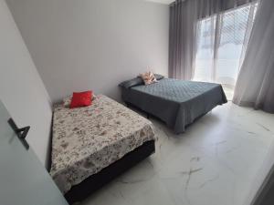 a bedroom with two beds and a window at BEIRA MAR I - TUPI - 15 metros da praia - 2 dormitórios com VARANDA - WI FI e acomoda até 8 pessoas - ESTACIONAMENTO Gratuito in Praia Grande