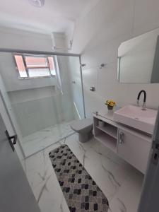 La salle de bains est pourvue d'un lavabo, de toilettes et d'un miroir. dans l'établissement BEIRA MAR I - TUPI - 15 metros da praia - 2 dormitórios com VARANDA - WI FI e acomoda até 8 pessoas - ESTACIONAMENTO Gratuito, à Praia Grande