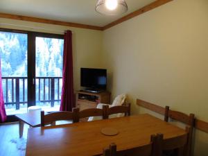 莫達訥的住宿－Chalet du Thabor - 3 Pièces pour 8 Personnes 591，一间带木桌和电视的用餐室