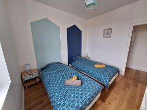 two beds in a small room with blue sheets at Appartement au cœur de la Côte de Granit Rose. in Trégastel +14 photos