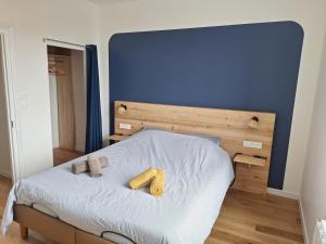 a bed with a blue headboard and two towels on it at Appartement au cœur de la Côte de Granit Rose. in Trégastel