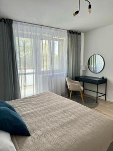 a bedroom with a bed and a desk and a mirror at Apartment ZANzi in Šamorín