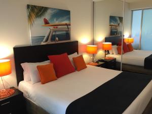 een slaapkamer met een groot bed met oranje kussens bij Cairns Private Apartments in Cairns